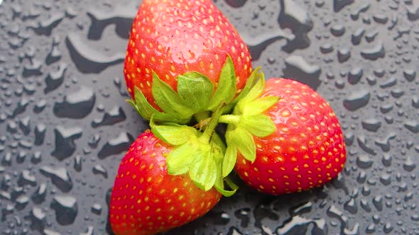 Top Ciew  Strawberry Covered with Water Droplets are Spinning on a Wet Table alt