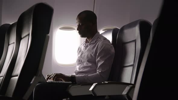 Man working on laptop computer on airplane