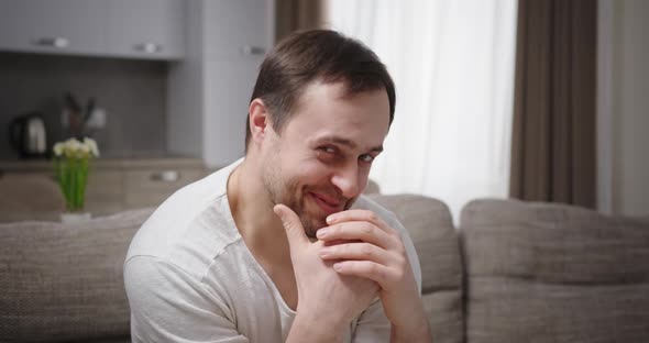 Actor Man Hides Face Closes Hands Feels Ashamed Smiles with a Grin Sitting at Home on the Couch alt