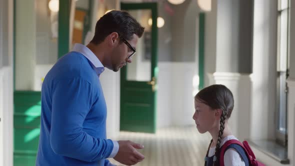 Side View of Indian Male Teacher Reprimanding Preteen Schoolgirl in Corridor alt