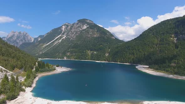 Aerial View of Lake Predil with Turquoise Water and Mountains in Background alt