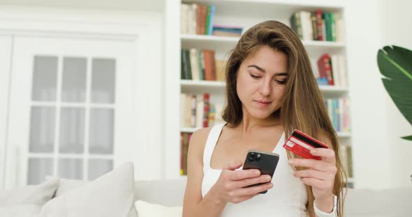 Portrait of Young Beautiful Woman Making Purchases Via the Internet Using a Smartphone and a Bank alt