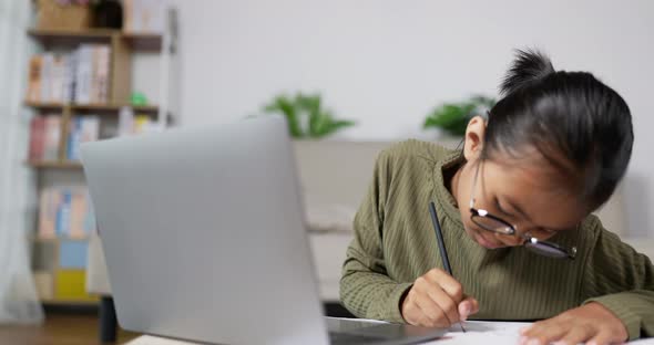 Happy girl kid studying online in living room alt