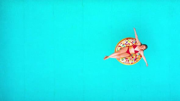 Aerial View of a Woman in Red Bikini Lying on a Donut in the Pool alt