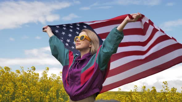 Woman with USA flag in yellow rapeseed field