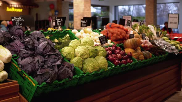 Fresh Vegetables with Price Tags on Supermarket Shelves. Cabbage, Onions, Potatoes, Pumpkin Are Sold alt