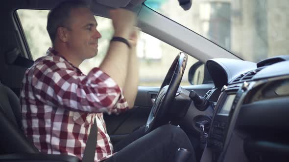 Side View of Cheerful Relaxed Happy Man Dancing Sitting on Driver's Seat in Automobile alt