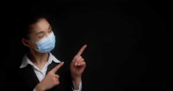Asian Woman in a Medical Mask Points to an Empty Space for your Advertisement