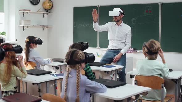Teacher Teaches an Interactive Lesson at Modern School Childs in Virtual Reality Glasses Learning in alt