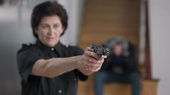 Female Hands Raising Holding Armed Gun with Blurred Policewoman and Desperate Burglar or Murderer at alt