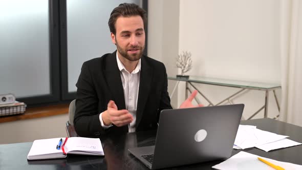 Smiling Young Businessman in Formal Wear Sitting at the Desk in Office alt