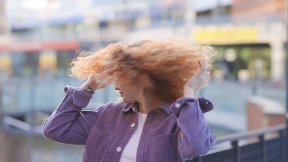 Young woman dancing and tossing hair in city