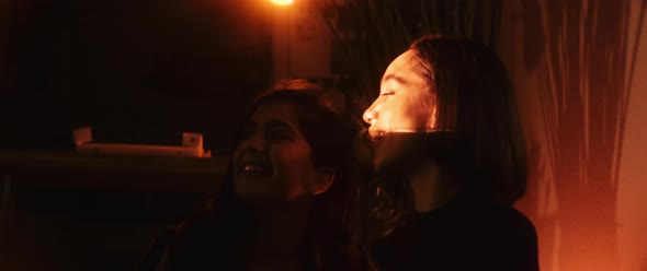 Two best friends hugging and dancing together in conrast of bright light source alt