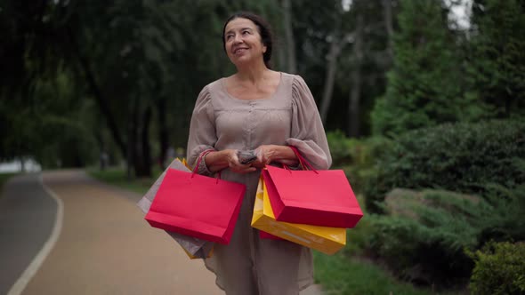 Wealthy Satisfied Senior Caucasian Woman with Shopping Bags Counting Cash Money Walking Away Leaving alt