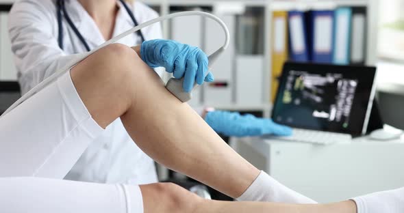 Doctor Conducts Ultrasound Examination of Knee Joint in Clinic Closeup alt