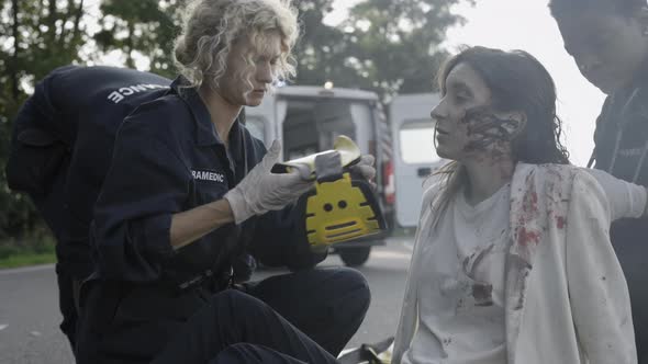 Team of Paramedics Providing First Aid for Woman on Road alt