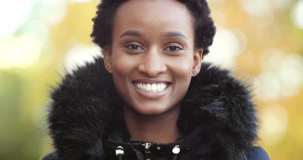 Portrait of Beautiful Black Woman Wears Warm Black Jacket Stands on Street in Autumn alt
