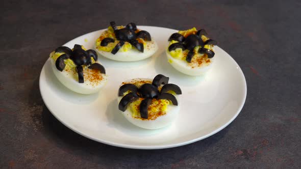 Spider Deviled Eggs on a White Plate. Healthy Halloween Snack Recipe.