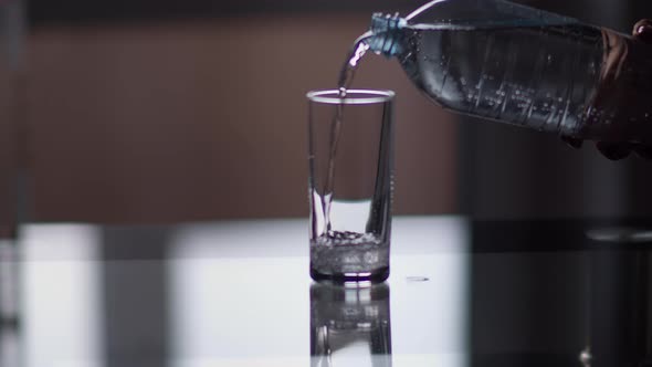 Sparkling Water Pouring From a Bottle Into a Glass in the Kitchen, Moving Camera