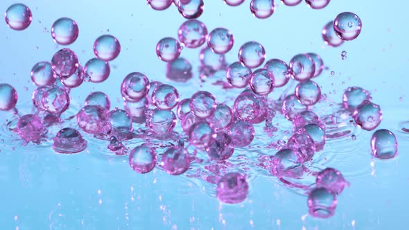 Super Slow Motion Shot of Neon Hydrogel Balls Bouncing on Glass with Water at 1000Fps alt