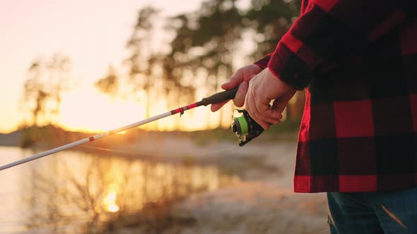 Fisherman is Catching Fish Alone in Sunset or Sunrise Closeup of Fishing Rod in Hands Calm and alt