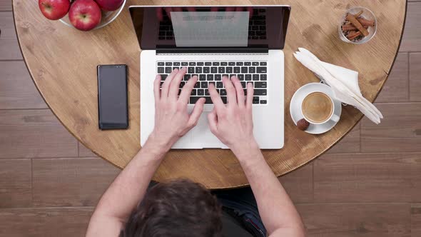 Top View of a Young Freelancer Writing an Article on His Laptop alt