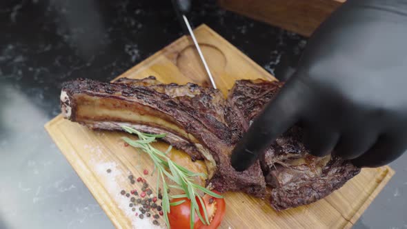 Waiter in Gloves Cuts a Juicy Steak