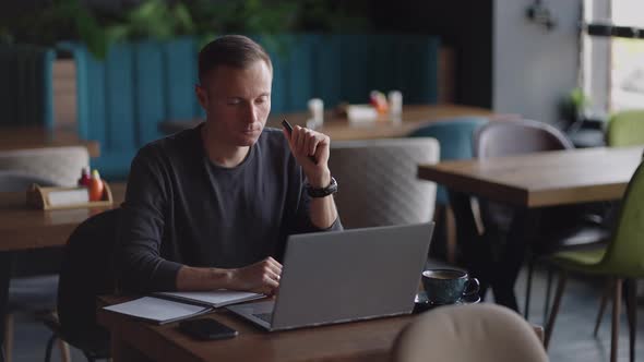 Thoughtful Serious Young Man Student Writer Sit at Home Office Desk with Laptop Thinking of alt