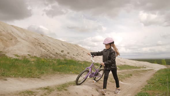 Cute Little Girl Bicyclist in Helmet Walk Pathway Rural Road with Her Bike. Recreation Time.