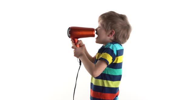 Little Boy in the Studio on a White Background Fooling Around with a Hairdryer, Screaming Into the