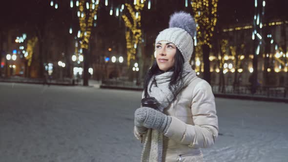 Girl in Warm Clothing with Cup of Coffee on Winter Square alt