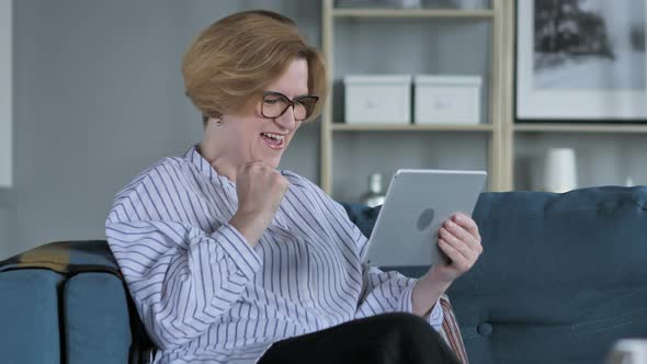 Woman Celebrating Success while Using Tablet alt