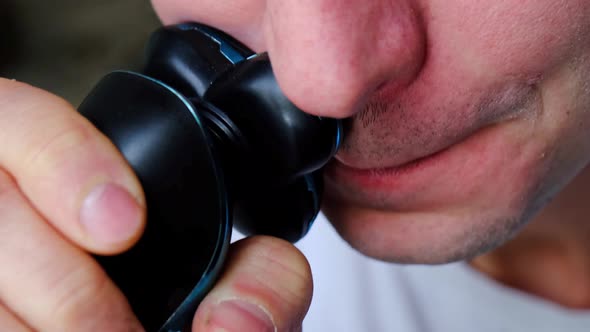 A man shaves with an electric razor close-up. Smooth shaving of light bristles. Slow Motion alt