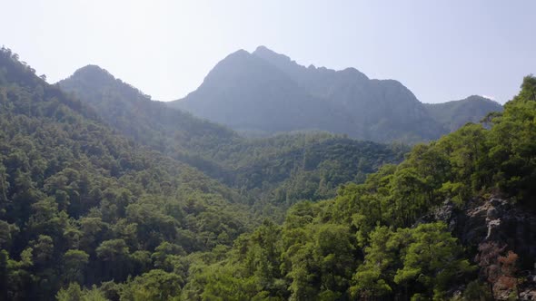Mountains Peaks Overgrown with Green Dense Forests Against Blue Sky alt