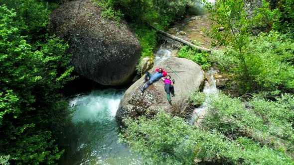 Man And Woman Lying On Stone In River alt