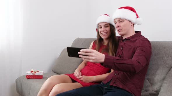 Young Couple Celebrating Christmas at Home. Talking Online by Smartphone. 