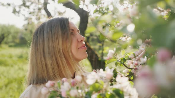 Young Woman Admiring Flowering Apple Trees in the Garden alt