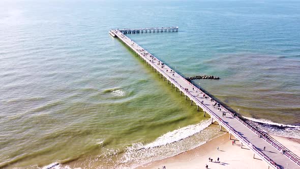 Palanga bridge on sunny day with many people, aerial tilting up view alt