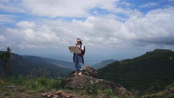 Backpacking female hiker stands on top of the mountain and enjoying the view. alt