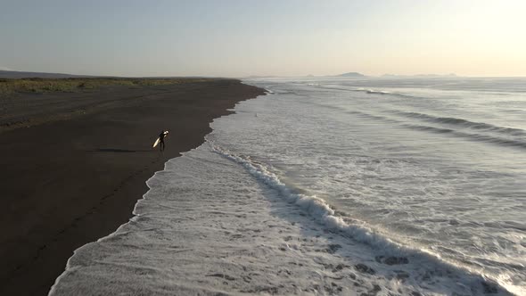 Aerial View Young Surfer Standing on Beach with Surf and Looking Ocean Horizon alt