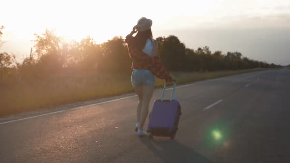 Young Woman with a Suitcase on Road. Funny Beautiful Girl Traveler. Travel Concept Video. alt
