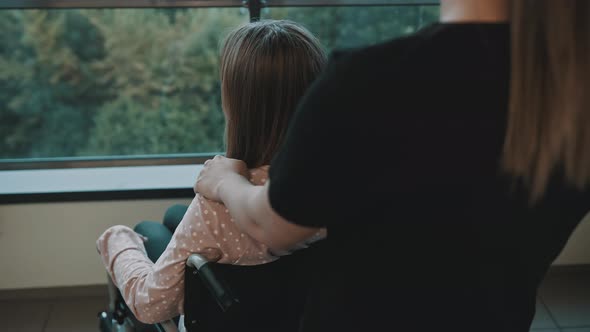 Carer, Woman Caressing Shoulder of the Young Woman in the Wheelchair on the Balcony alt