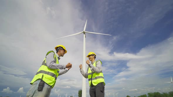 Teamwork of Asian windmill engineer group, worker high five, work on site at wind turbines alt