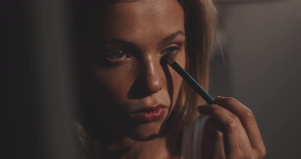 Close up of a beautiful girl putting on make up with the brush alt