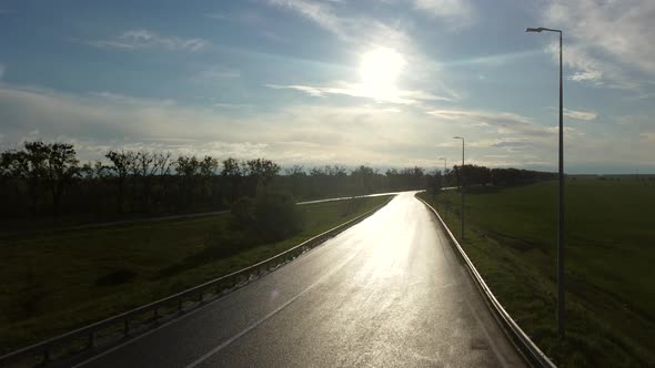 Drone Rises Above Wet Asphalt Road for Cars Between Sown Fields alt