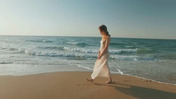 Confident Blonde Woman Is Walking Alone on Seashore in Summer Day