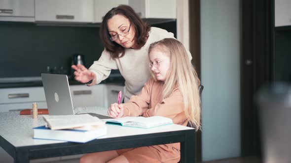 A Kind Grandmother in Eyeglasses Helping Her Granddaughter with Her Homework alt