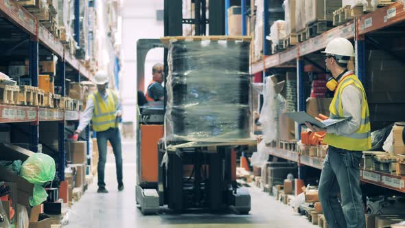 Warehouse Worker on a Forklift Getting Up Goods To Upper Shelf alt