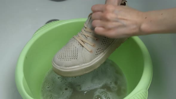 Woman is Washing Sport Shoes in Basin Using Sponge By Hands Closeup Hands