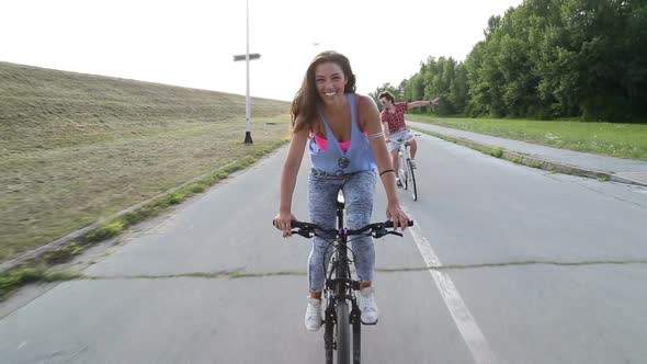 Beautiful woman sending kisses while cycling with friends alt